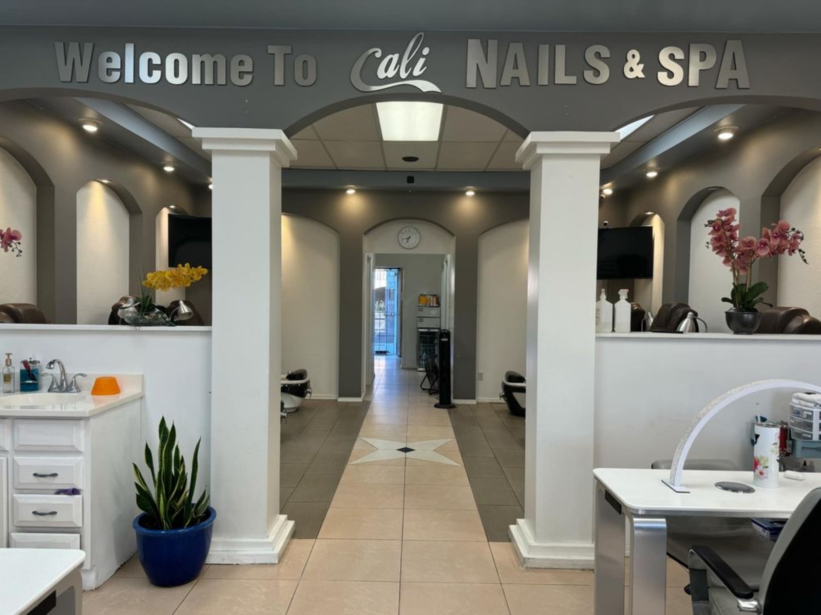 Inside Cali Nails & Spa, with arched pedicure alcoves and orchids